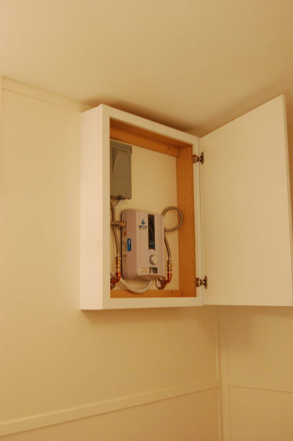Wall-mounted tankless water heater in a bathroom cabinet