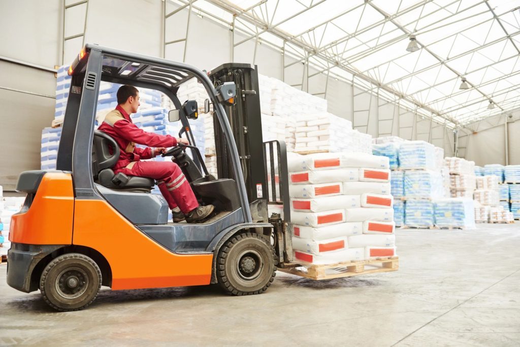 Forklift moving a pallet of bagged goods in a warehouse